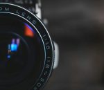 Detailed close-up of a vintage camera lens capturing intricate reflections in a dark setting.